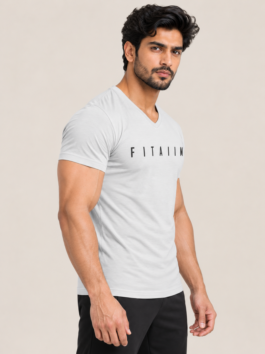 A muscular man wearing a light gray v-neck t-shirt with the brand name 'FITAIIM' printed in black across the chest, paired with black pants, set against a solid beige background.