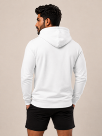 A man shown from the back wearing a plain white pullover hoodie and black athletic shorts, standing against a solid light beige studio background.