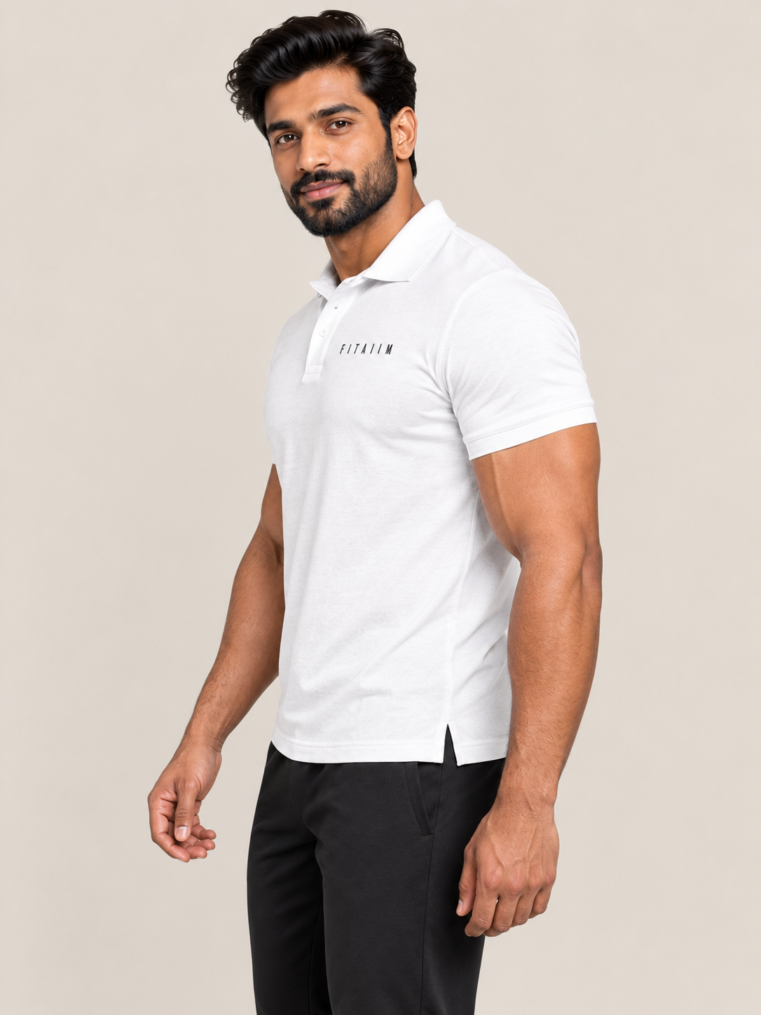 A man modeling a WHITE short-sleeve polo shirt with 'FITAIIM' printed on the chest, paired with black joggers and white sneakers, against a solid beige background.