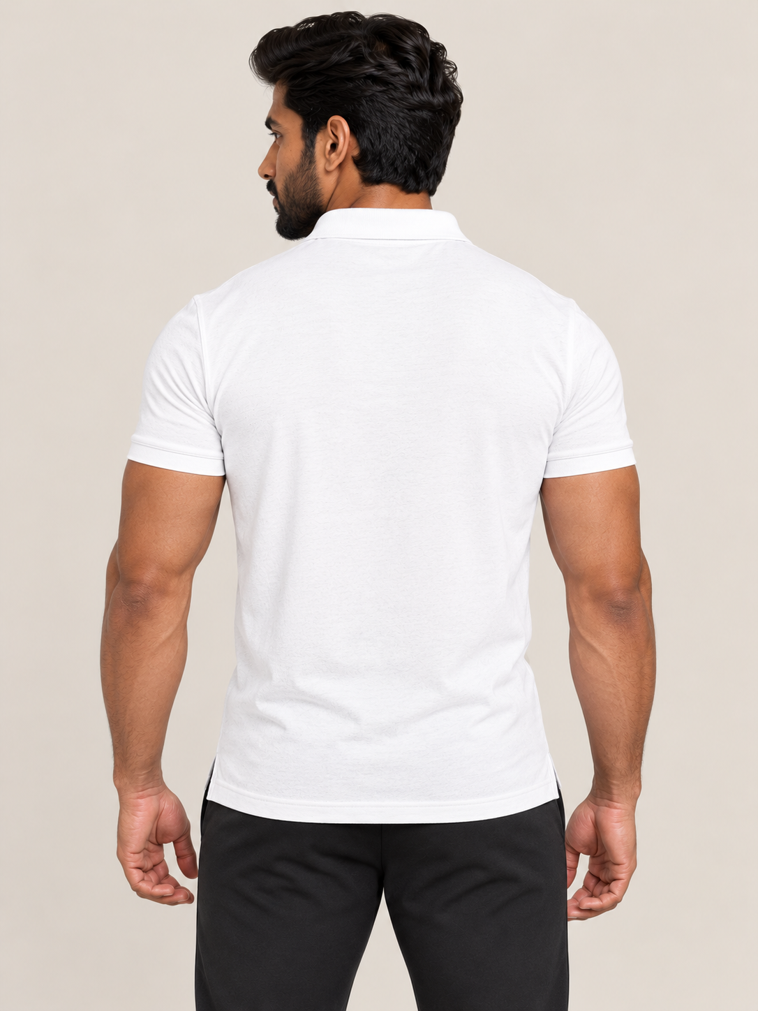 A man shown from the back wearing a plain white short-sleeve polo shirt and black pants, standing against a light beige studio background.