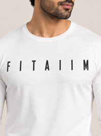 A close-up of a man wearing a white long-sleeve t-shirt with the name 'FITAIIM' printed in bold black capital letters across the chest, set against a plain beige background.