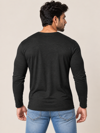 A man wearing a black long-sleeve crewneck t-shirt and blue jeans, shown from a rear three-quarter view against a solid light beige background.