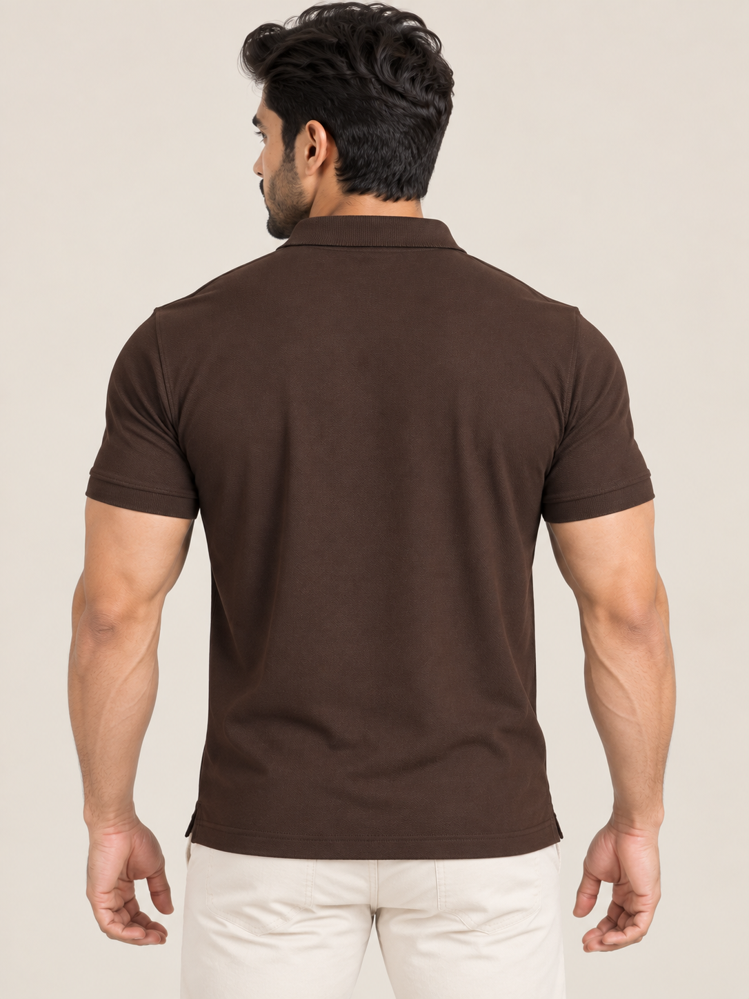 A man shown from the back wearing a dark brown short-sleeve polo shirt and off-white trousers, set against a plain beige studio background.