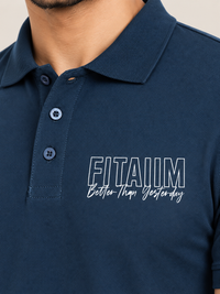 Close-up of a man wearing a navy blue polo shirt with a white graphic print on the chest that reads 'FITAIIM Better Than Yesterday'.