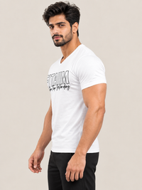 A muscular man wearing a white v-neck t-shirt with a black graphic print that reads 'FITAIIM BETTER THAN YESTERDAY  on the front, posed against a solid light beige background.