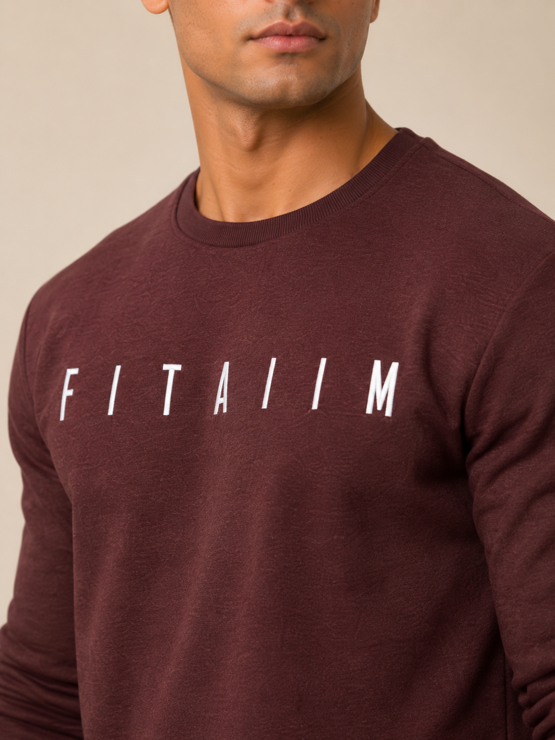 A close-up of a person wearing a maroon sweatshirt with a white graphic print on the chest that reads 'FITAIIM' in a bold, blocky font.
