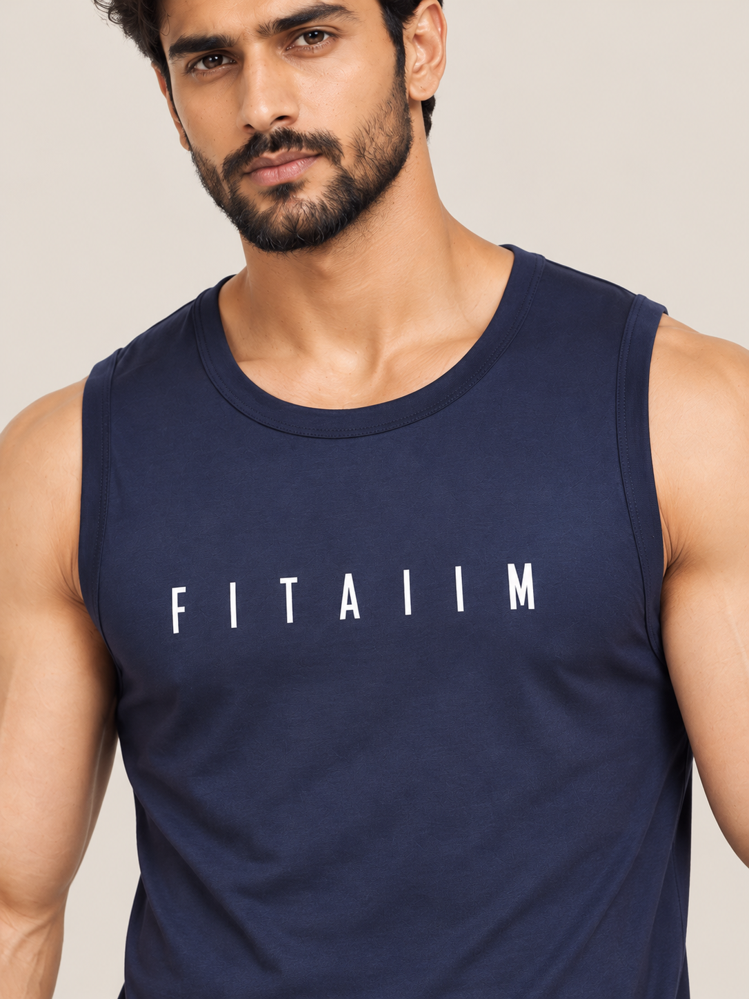 A close-up of a man wearing a navy blue sleeveless tank top with the word 'FITAIIM' printed in white across the chest, set against a plain beige background.