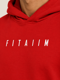 A close-up of a person wearing a bright red hoodie with the word 'FITAIIM' printed in white across the chest.