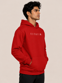 A man wearing a bright red pullover hoodie with the word 'FITAIIM' printed in white across the chest, posed against a solid light beige background.