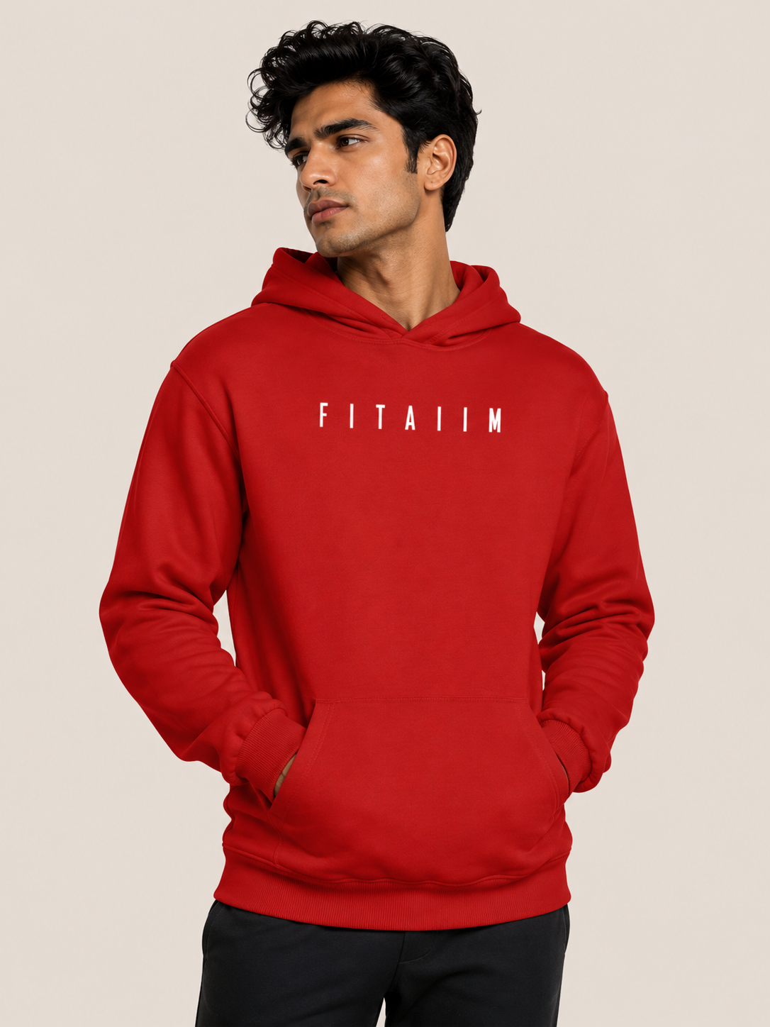 A man wearing a bright red pullover hoodie with the word 'FITAIIM' printed in white block letters across the chest, posed against a solid light beige background.