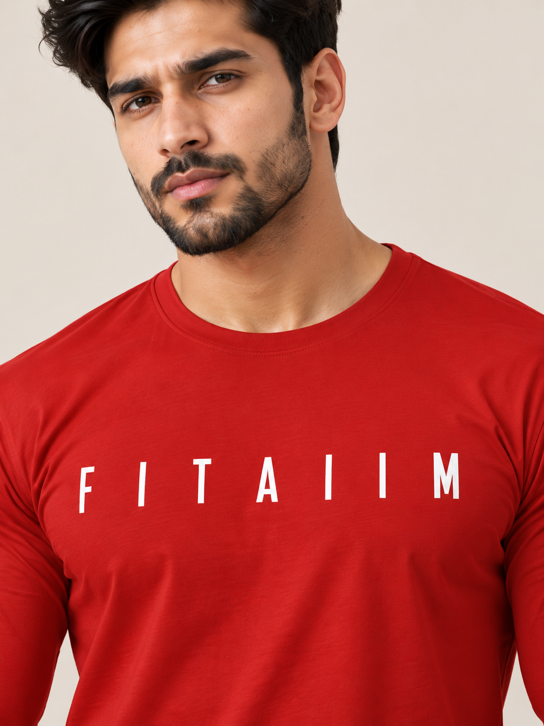 A close-up of a man wearing a red long-sleeve t-shirt with the name 'FITAIIM' printed in white capital letters across the chest, set against a plain beige background.