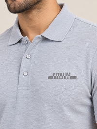 A close-up of a man wearing a GREY short-sleeve polo shirt with a gray and white 'FITAIIM' graphic printed on the left chest.