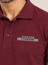 A close-up of a man wearing a MAROON short-sleeve polo shirt with a gray and white 'FITAIIM' graphic printed on the left chest.