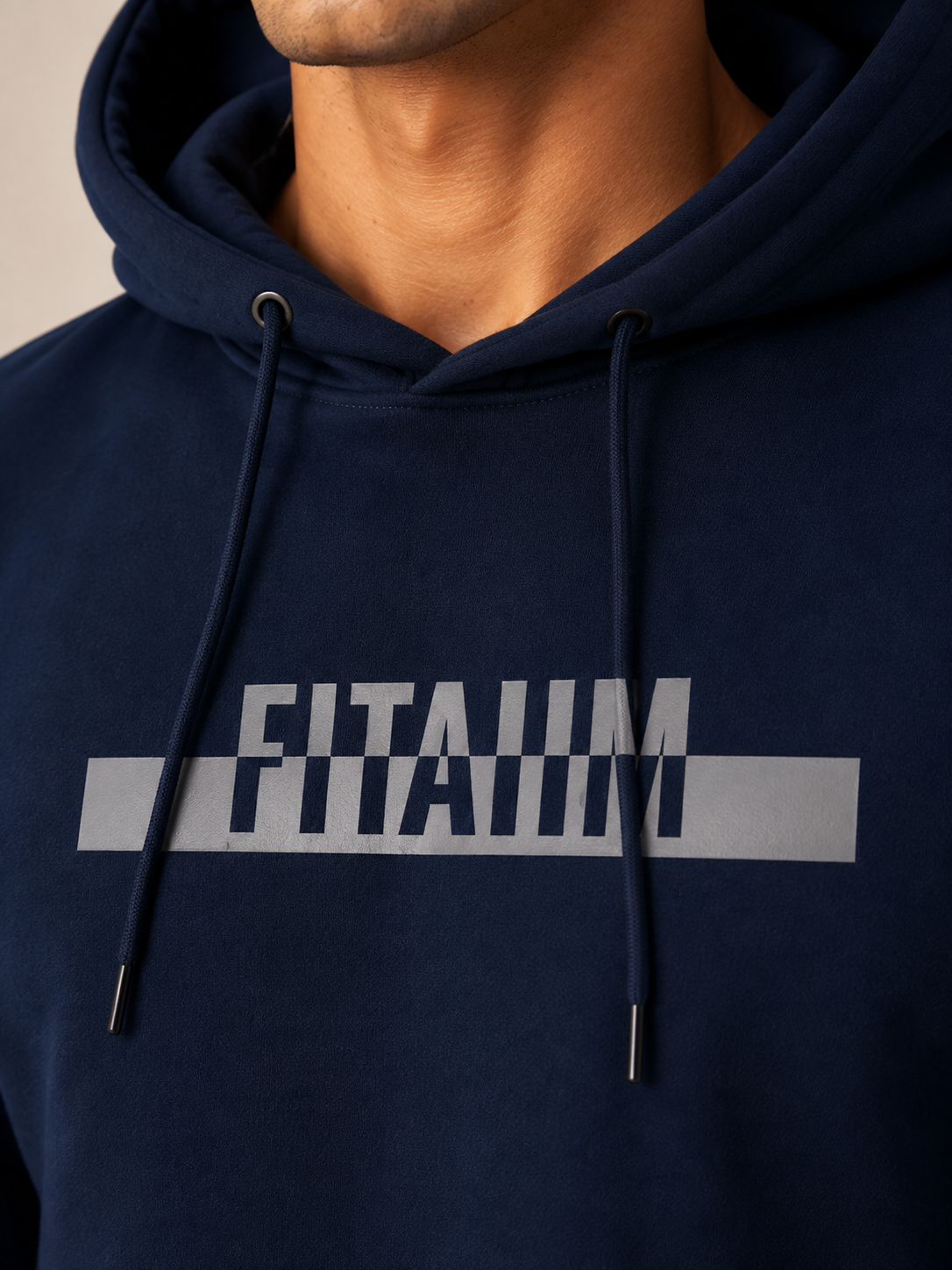 A close-up of a person wearing a navy blue hoodie with a large white graphic text print reading 'FITAIIM' across the chest.