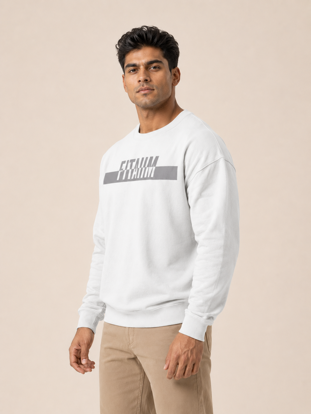 A man wearing a white sweatshirt with a gray and white graphic print on the chest, posed against a solid beige studio background.