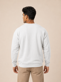 A man viewed from the back wearing a plain white sweatshirt and matching beige pants against a warm beige studio background.